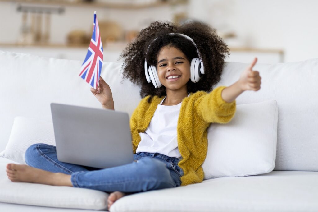 Happy black girl with computer on lap showing UK flag